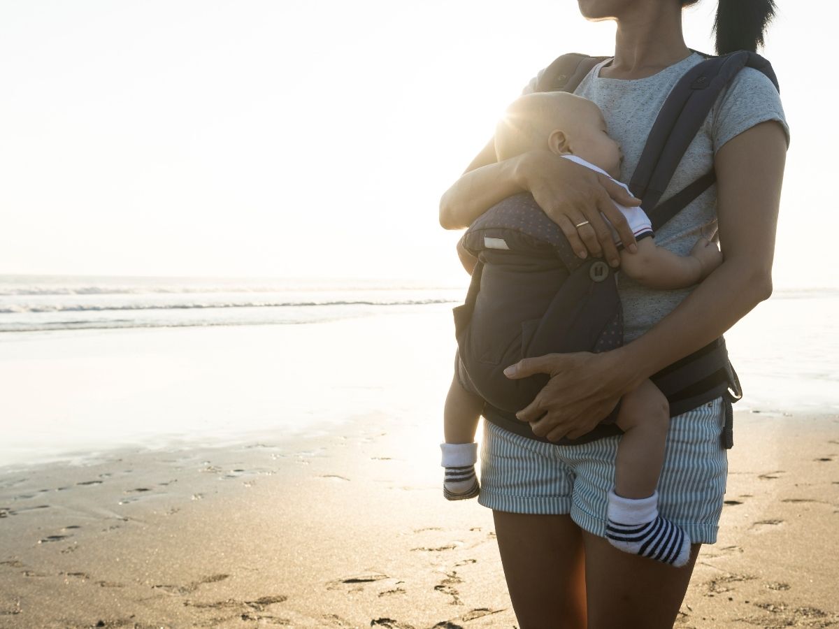 Woman using baby carrier for travel on beach