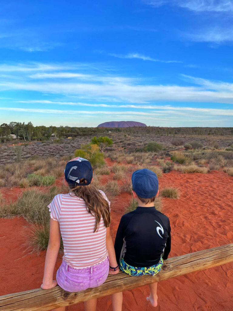 Kids sitting looking at Uluru in the distance