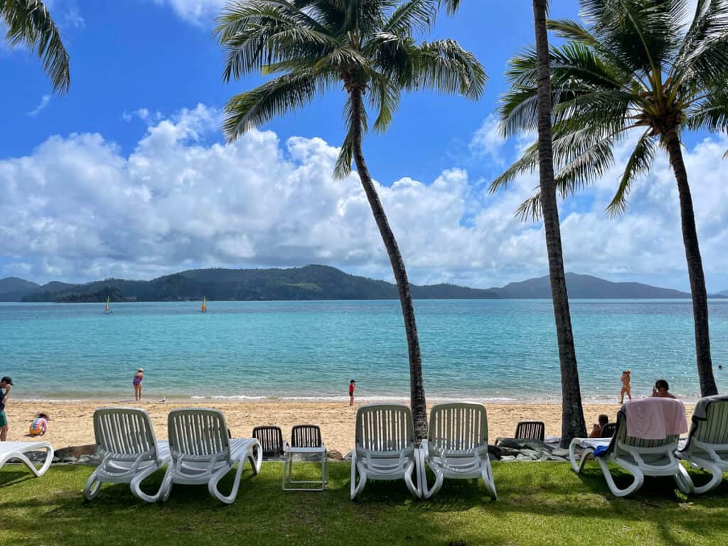 Beach in the Whitsundays with palm trees and sunloungers.