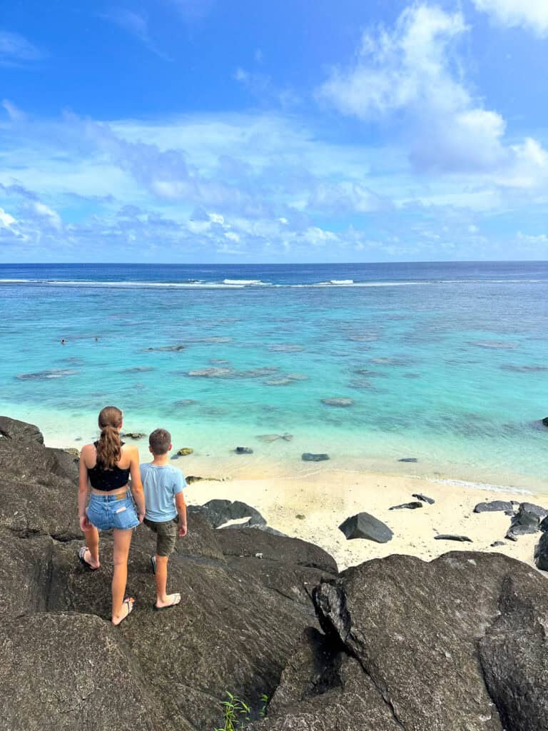 Kids looking over a blue ocean in the Cook Islands.