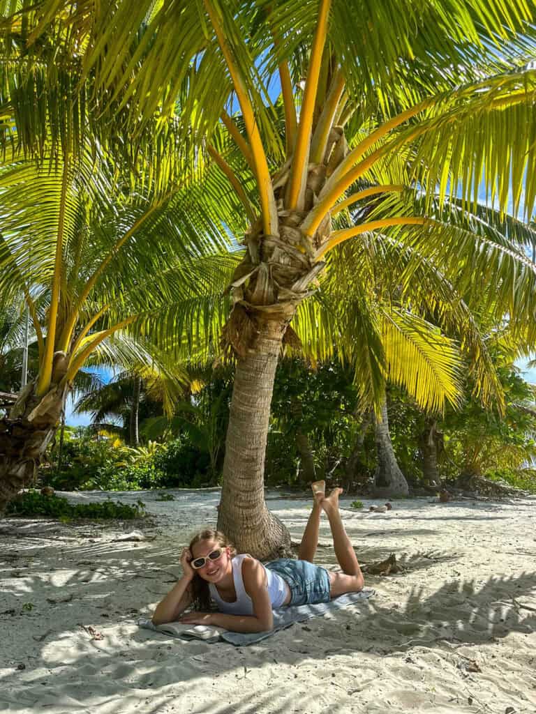 Girl relaxing under a palm tree in the Cook Islands.